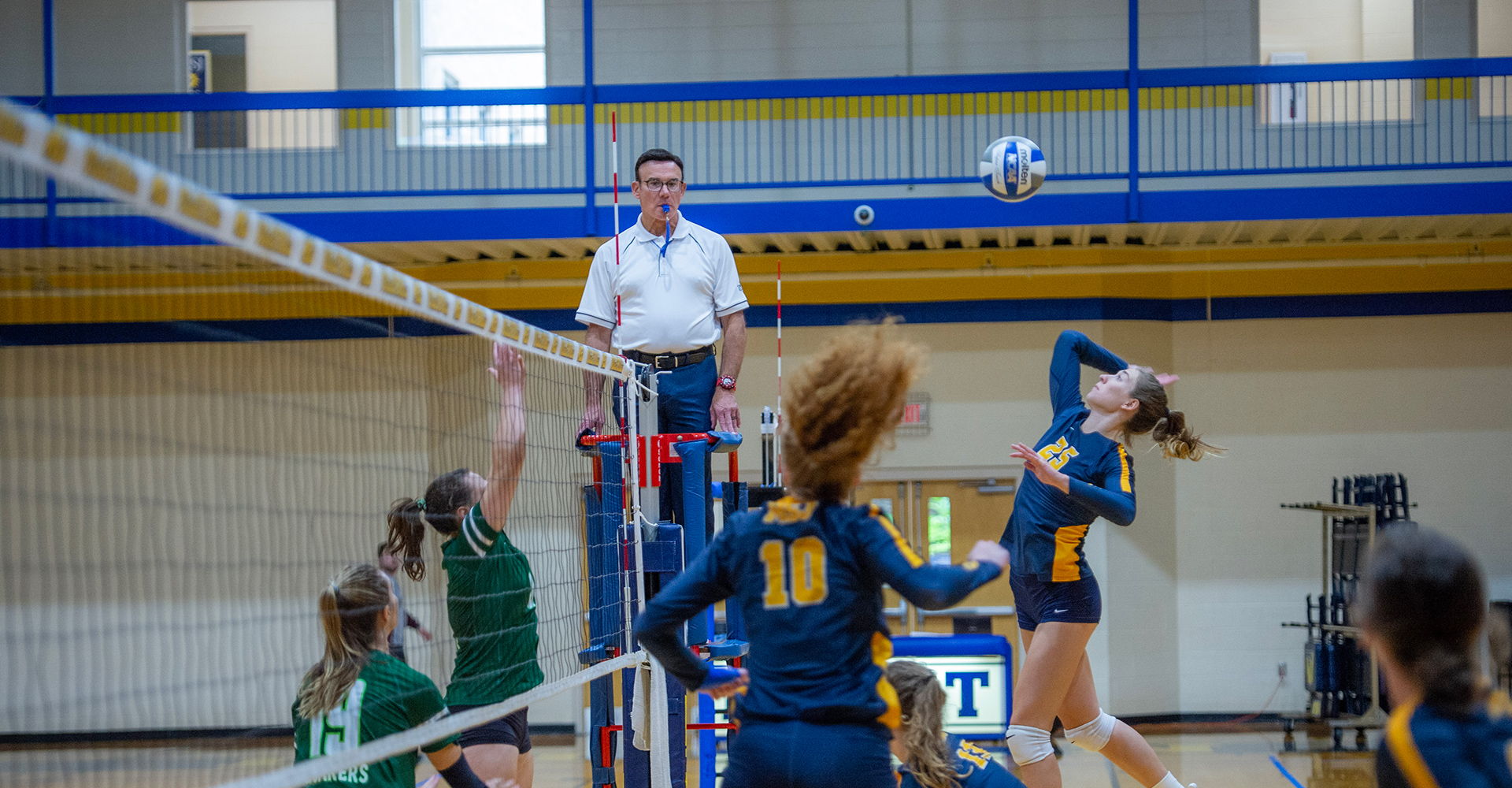 MSJ volleyball player spiking ball over net at msj gym.