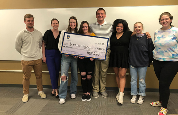 student philanthropy group project holding check