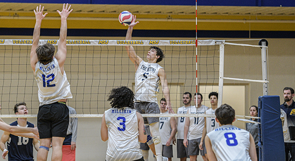 Male volleyballer in Mount jersey spikes the ball over the net