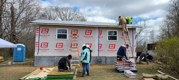 A group of people working on a small house