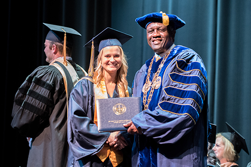 Female graduate receiving diploma from President Williams