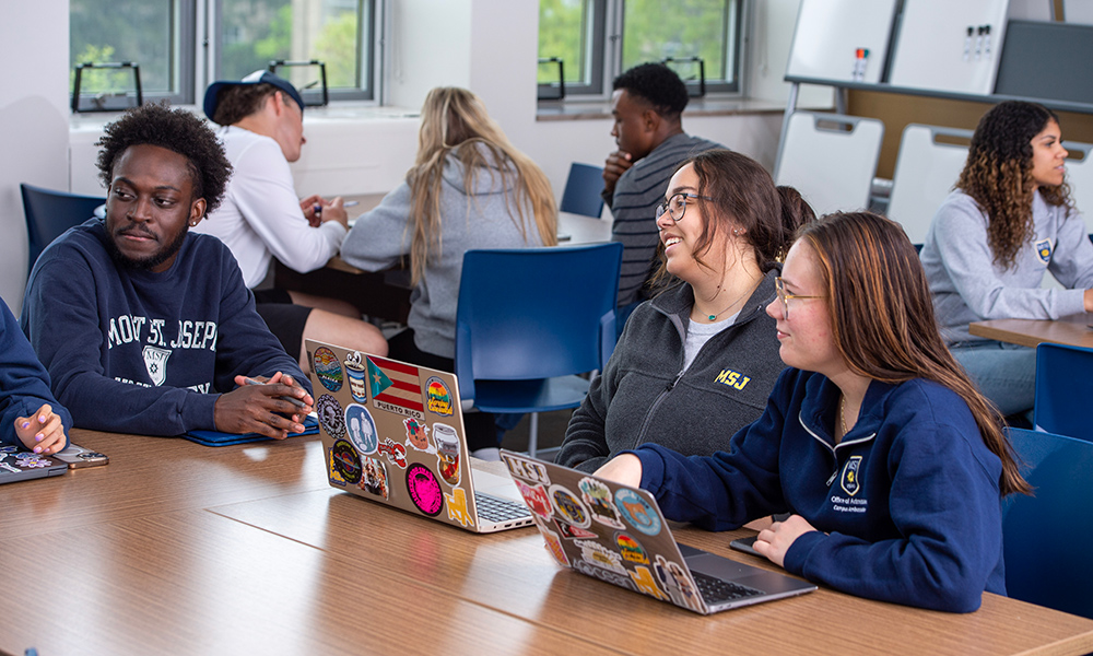 students at desks smiling on laptops