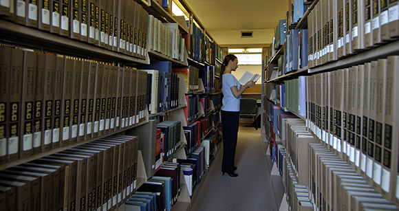 woman holding a book by library bookshelves