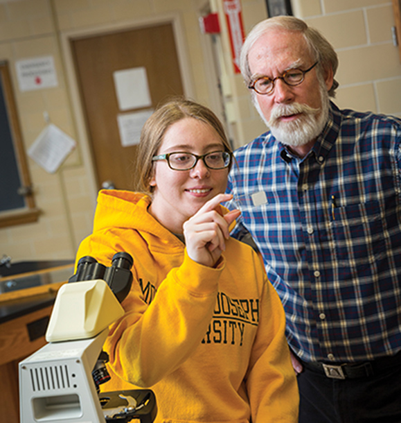MSJ female student examining content under a microscope with professor Dr. Gene Kritsky.