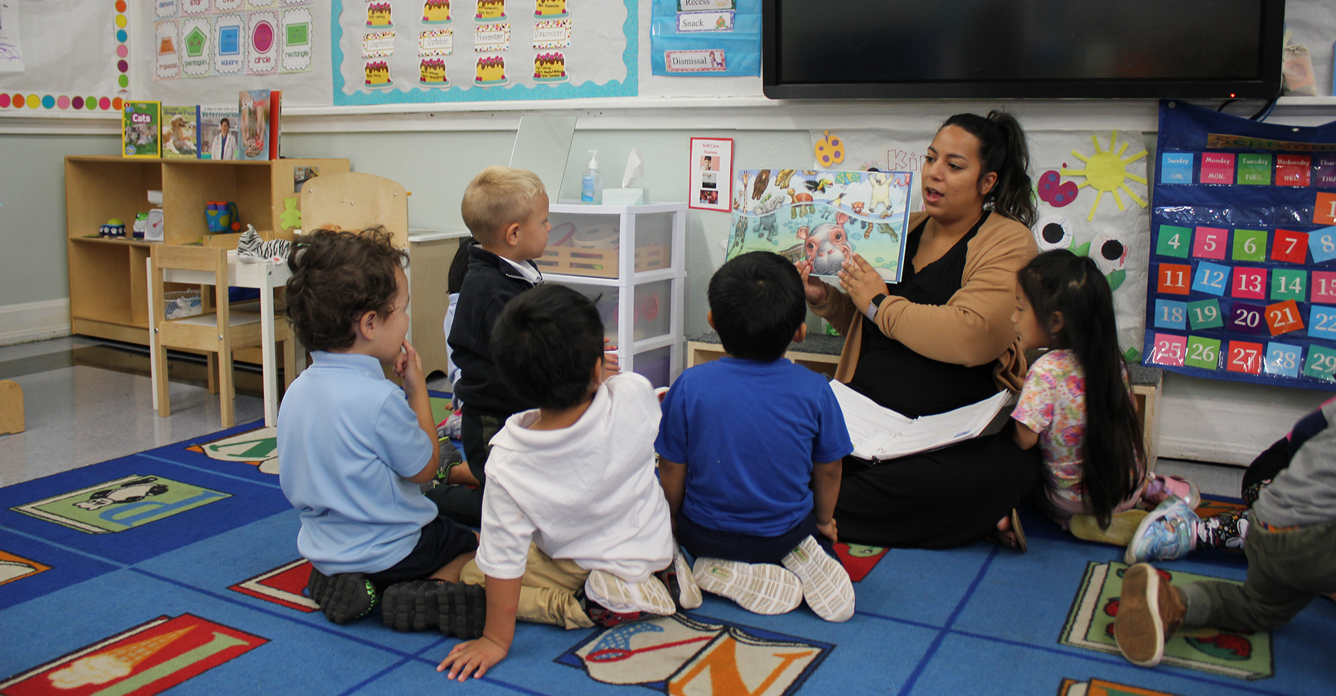 female teacher reading to kids in classroom.