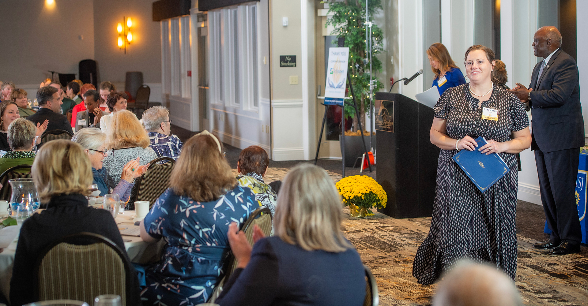 people clapping in a reception hall for a woman and her award