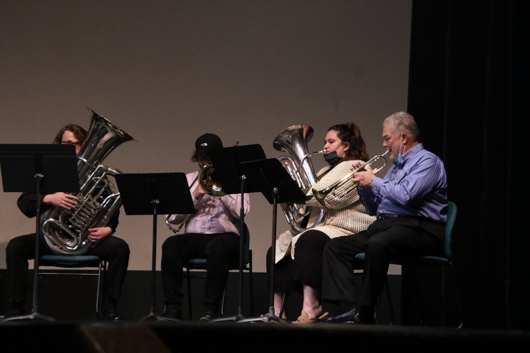 brass quartet performing on university theatre stage.