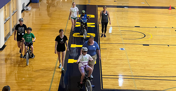 Mount St. Joseph University hosting bike camp, children learning how to ride bikes in Harrington Gym.