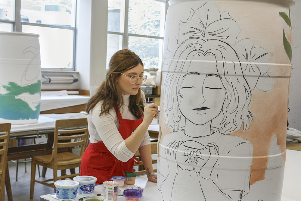 art guild students in art building in front of body of work