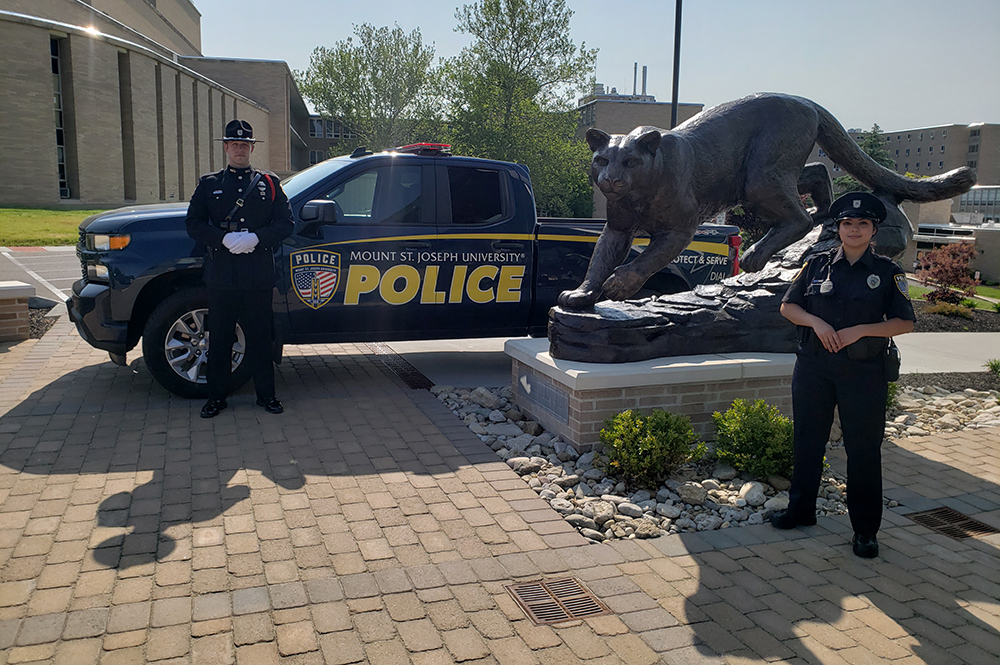 Two MSJ campus police standing in front of police truck and Lions Sculpture